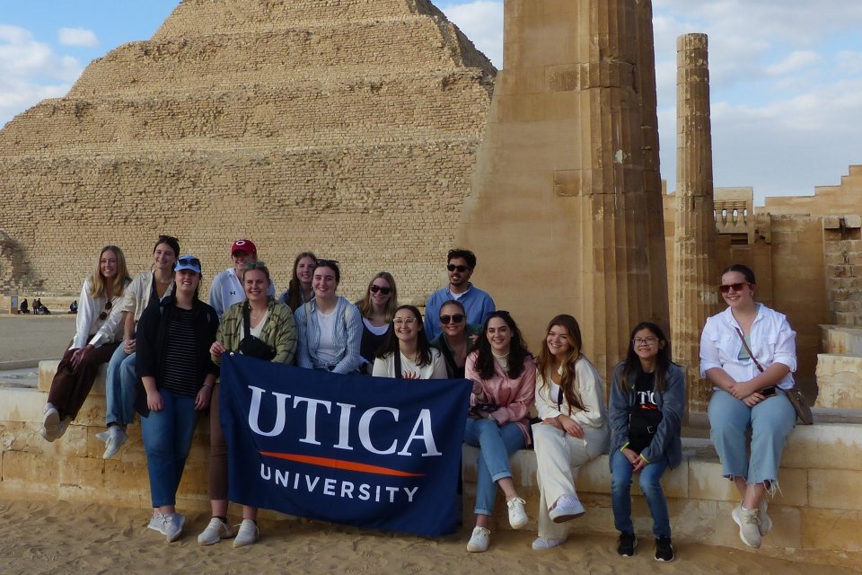 Students hold up a Utica University banner at Saqqara during a January 2023 trip to Egypt.