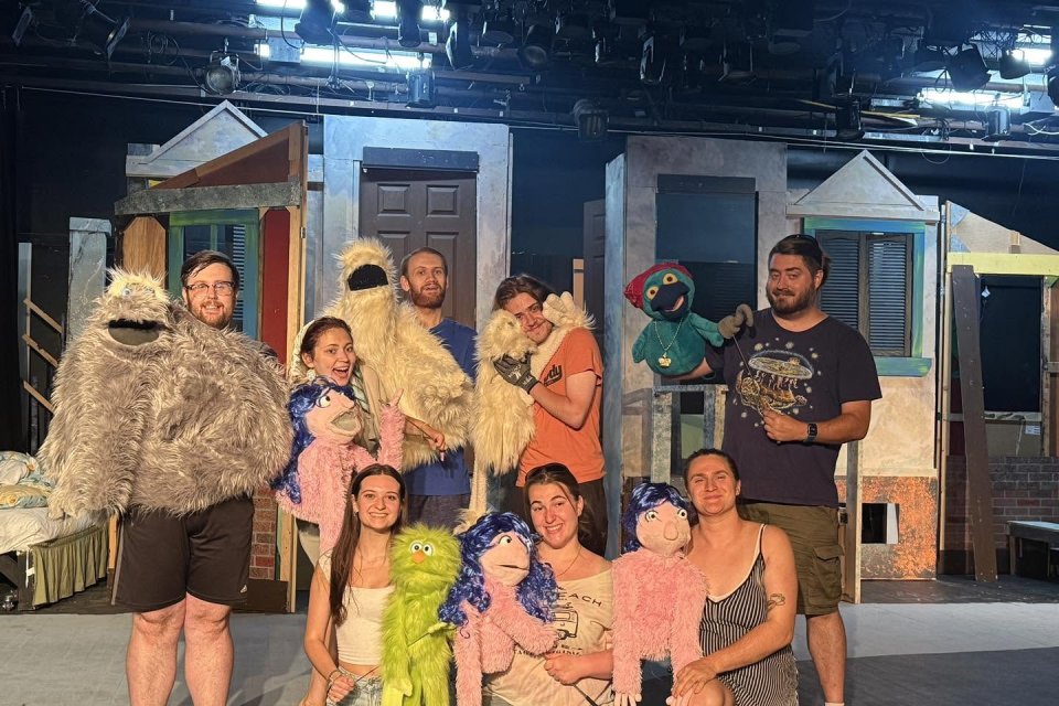 Members of the cast and their puppet companions on the stage in Strebel Auditorium for Avenue Q.